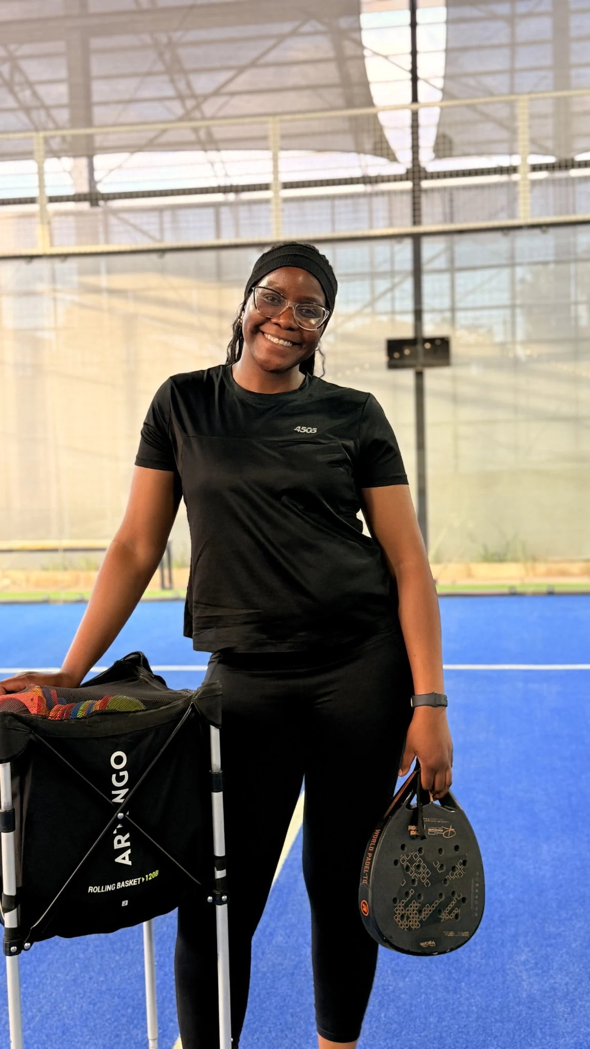 Tonia on a padel court with her racket and practice equipment.